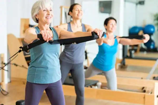 Toning Arms After 60: Empowering Womens Fitness Through Effective Weight Training 2 older woman doing weight training Stratford-upon-Avon and resistance in the gym to tone upper arms